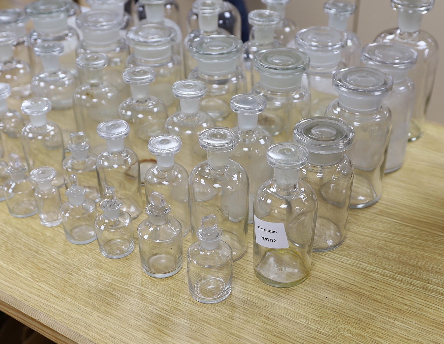 A large collection of clear glass chemist's bottles